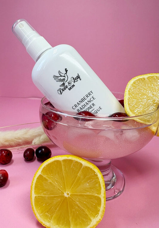 White bottle labeled 'Dote & Leaf' with cranberries and lemons on a pink background