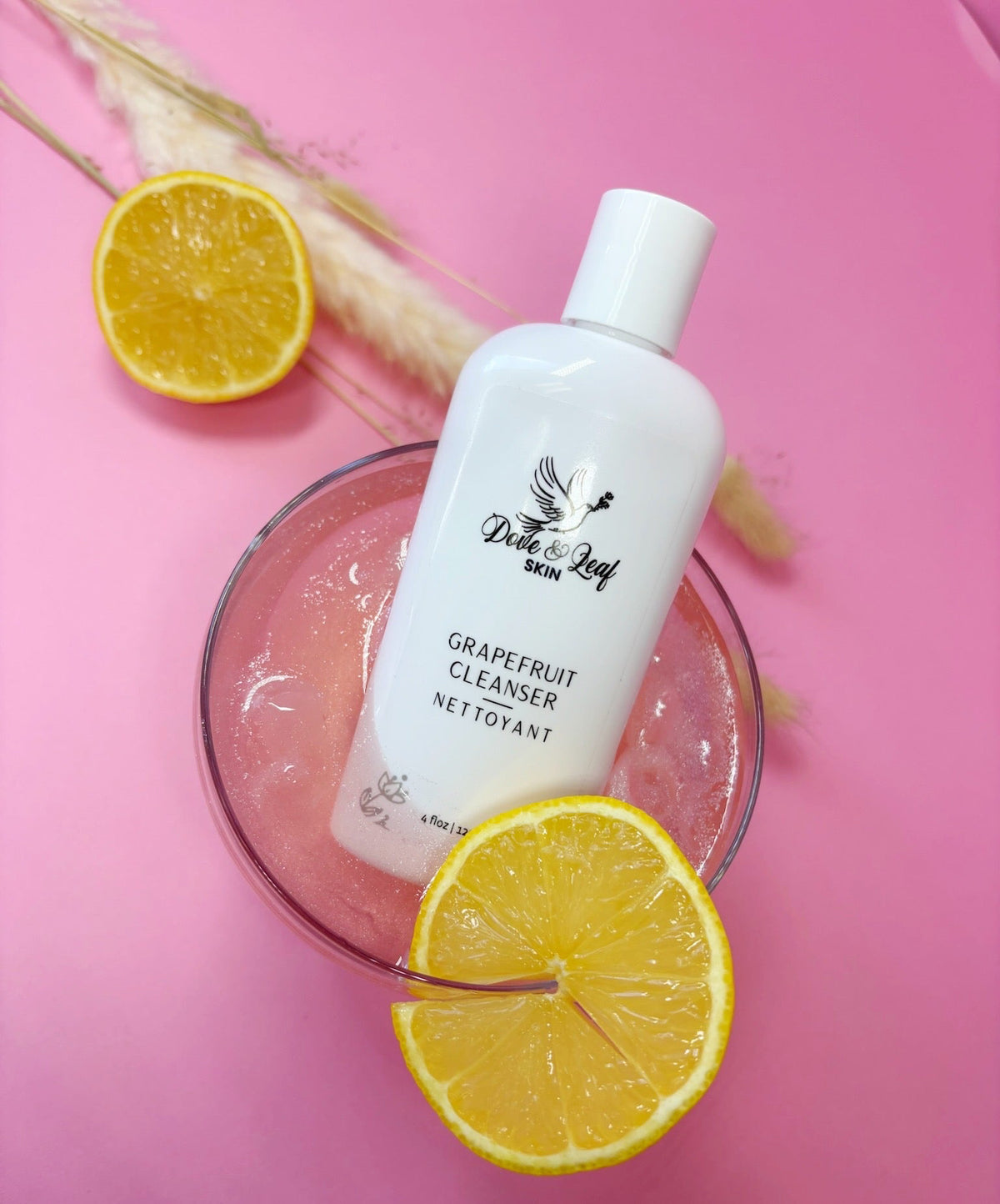 Grapefruit cleanser bottle with lemon slices on a pink background