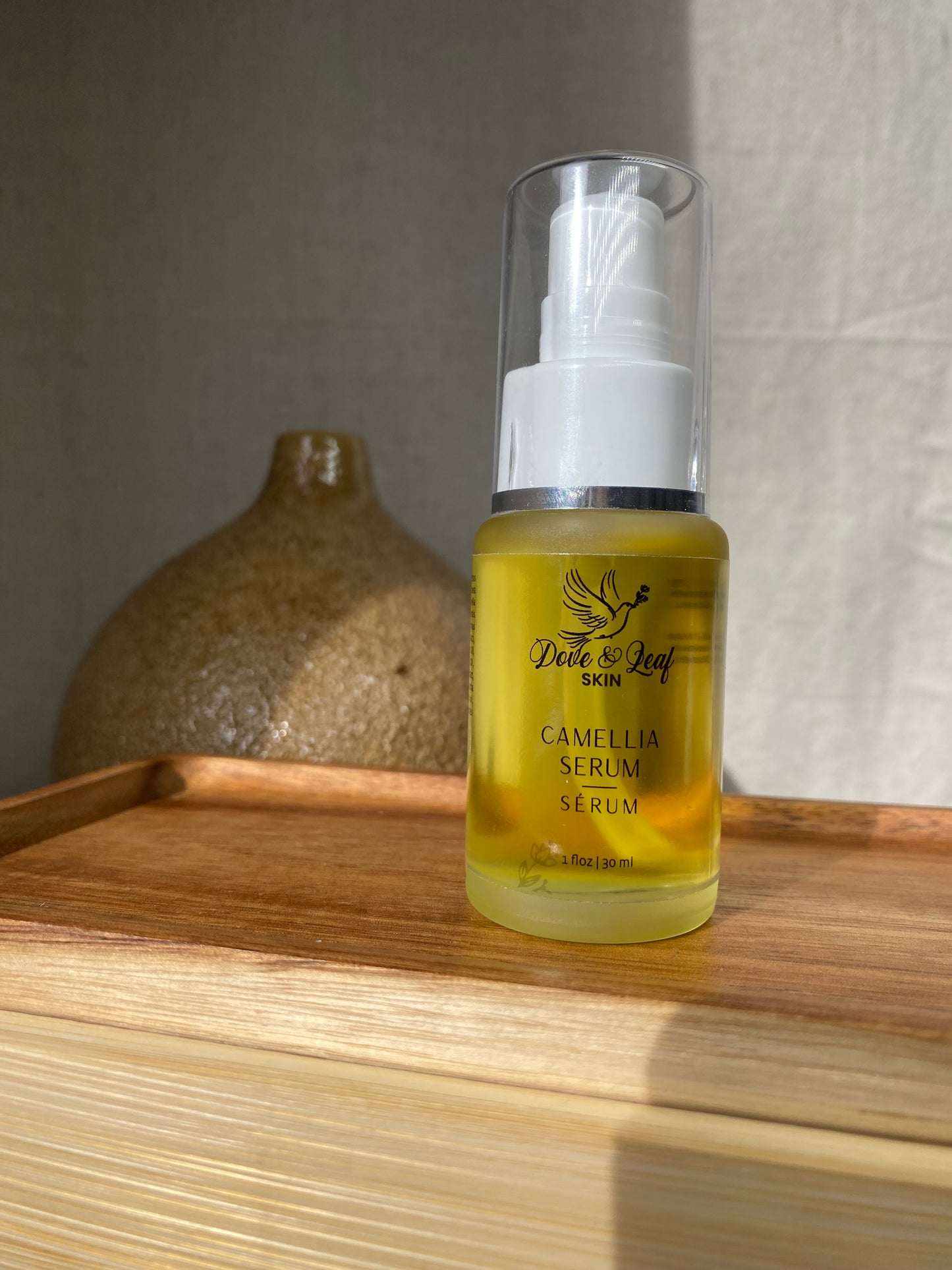 Bottle of Camellia Serum on a wooden surface