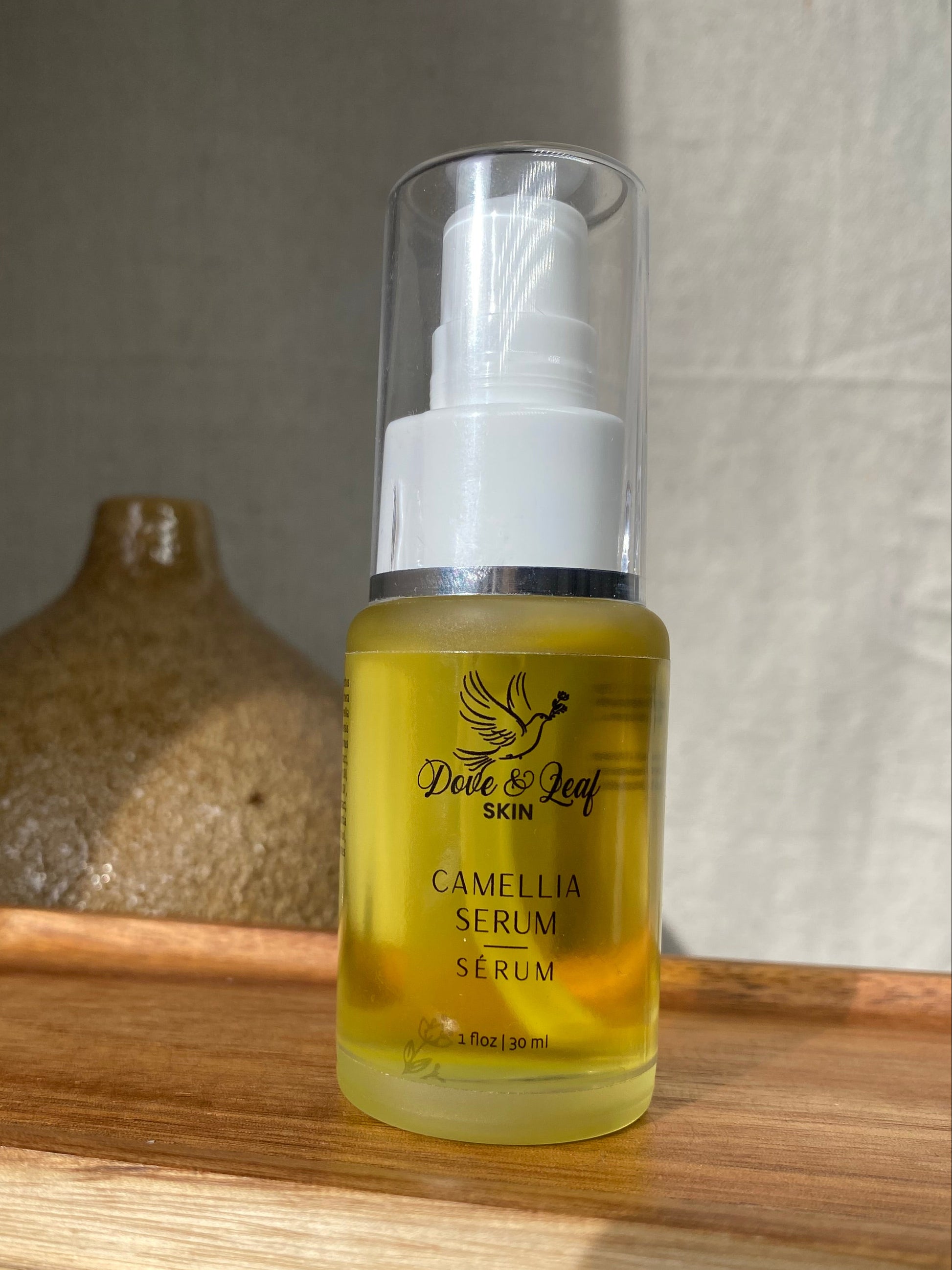 Bottle of Camellia Serum on a wooden surface