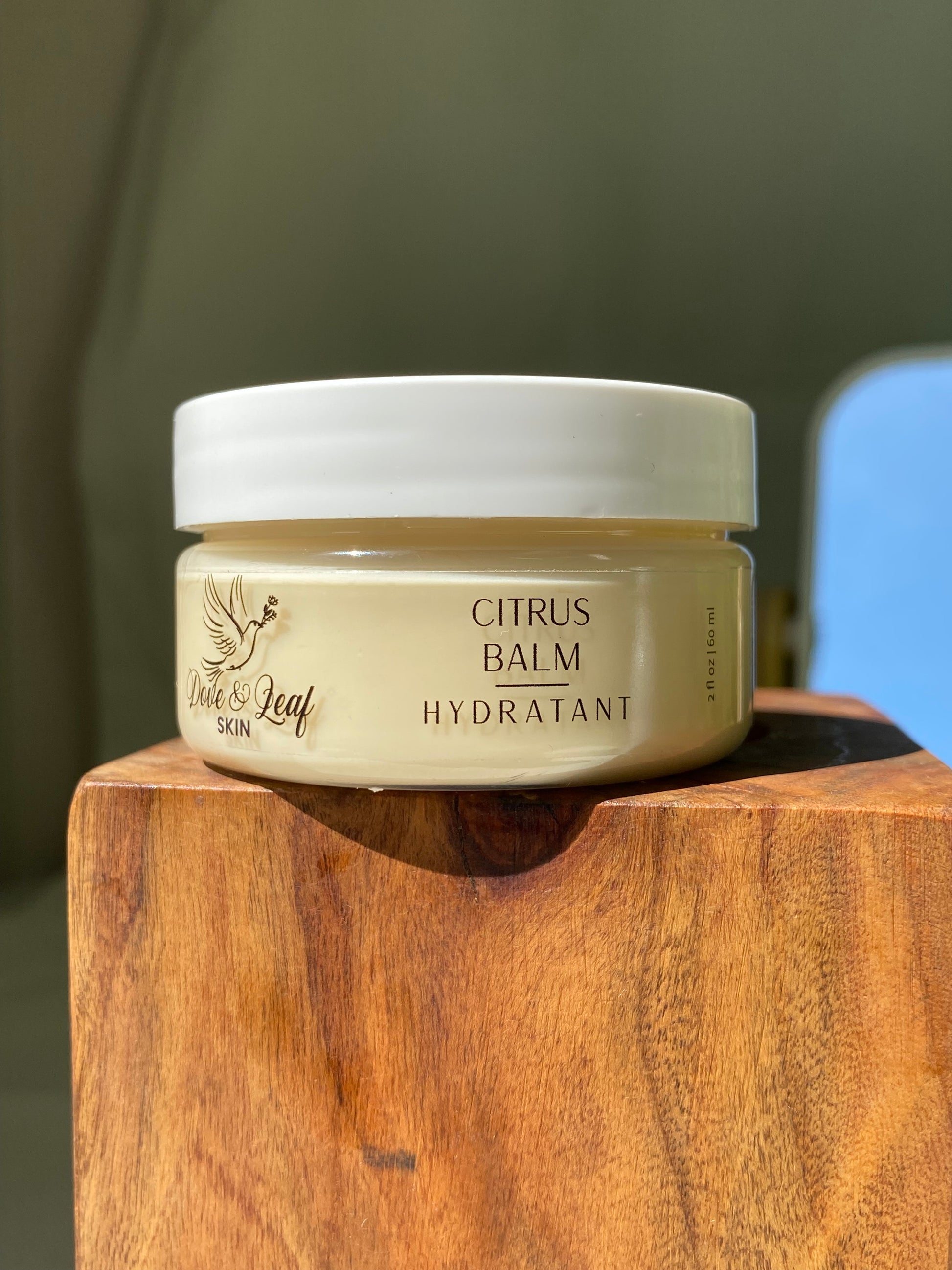 Jar of citrus balm on a wooden surface with a blurred background