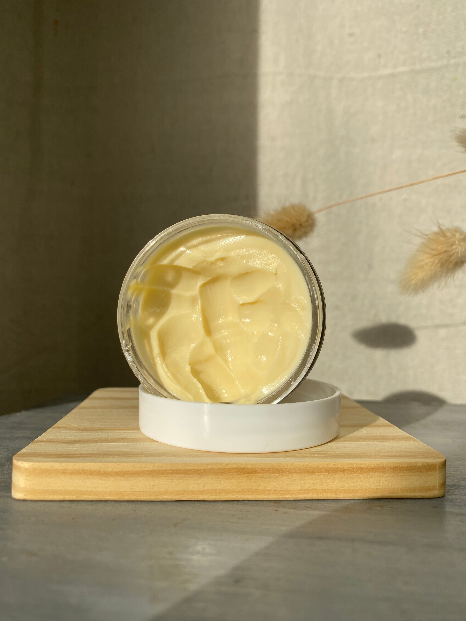 Jar of cream on a wooden block with a neutral background