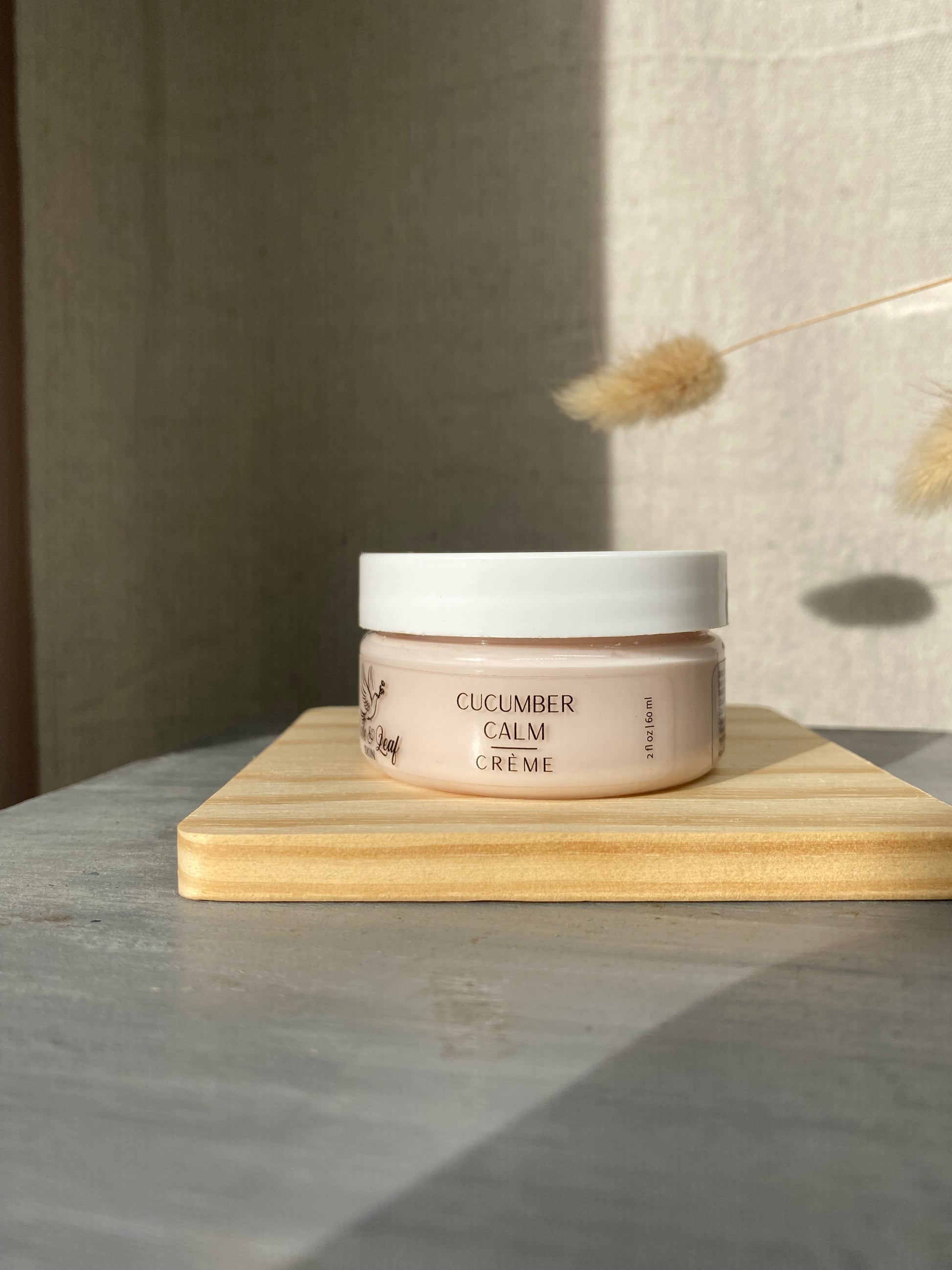 Jar of cucumber calm crème on a wooden shelf with a neutral background