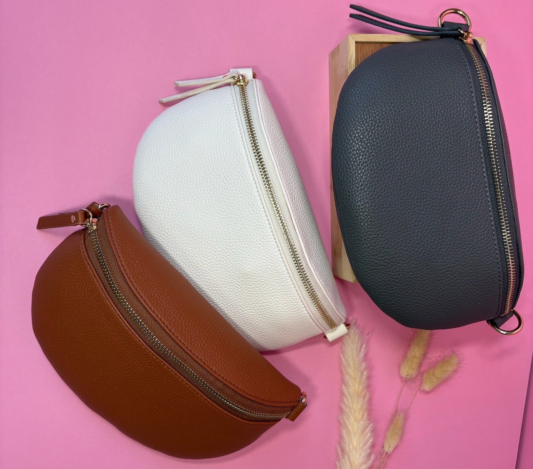 Four round pouches in brown, white, and black on a pink background