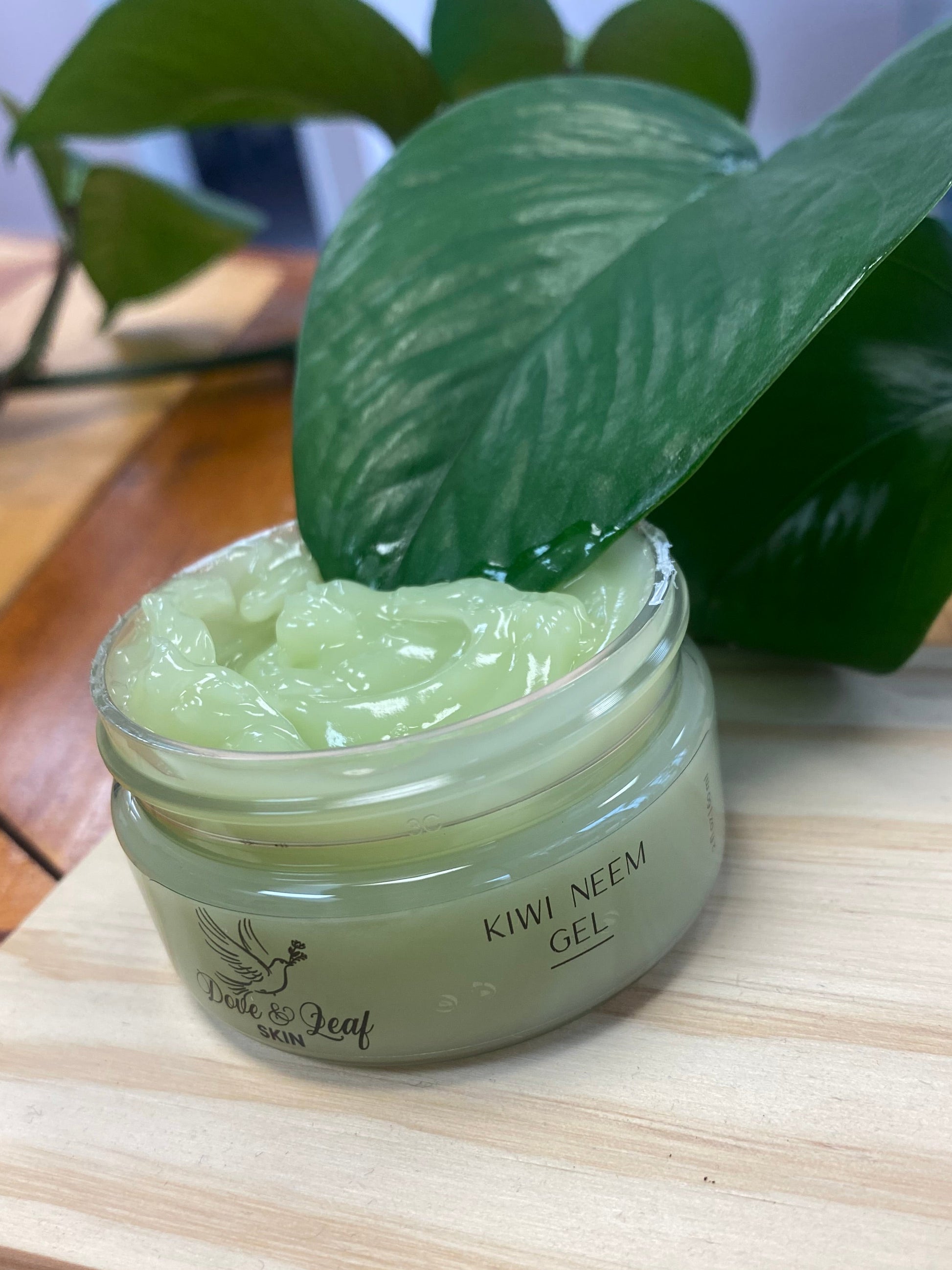 Jar of Kiwi neem gel on a wooden surface with a plant in the background