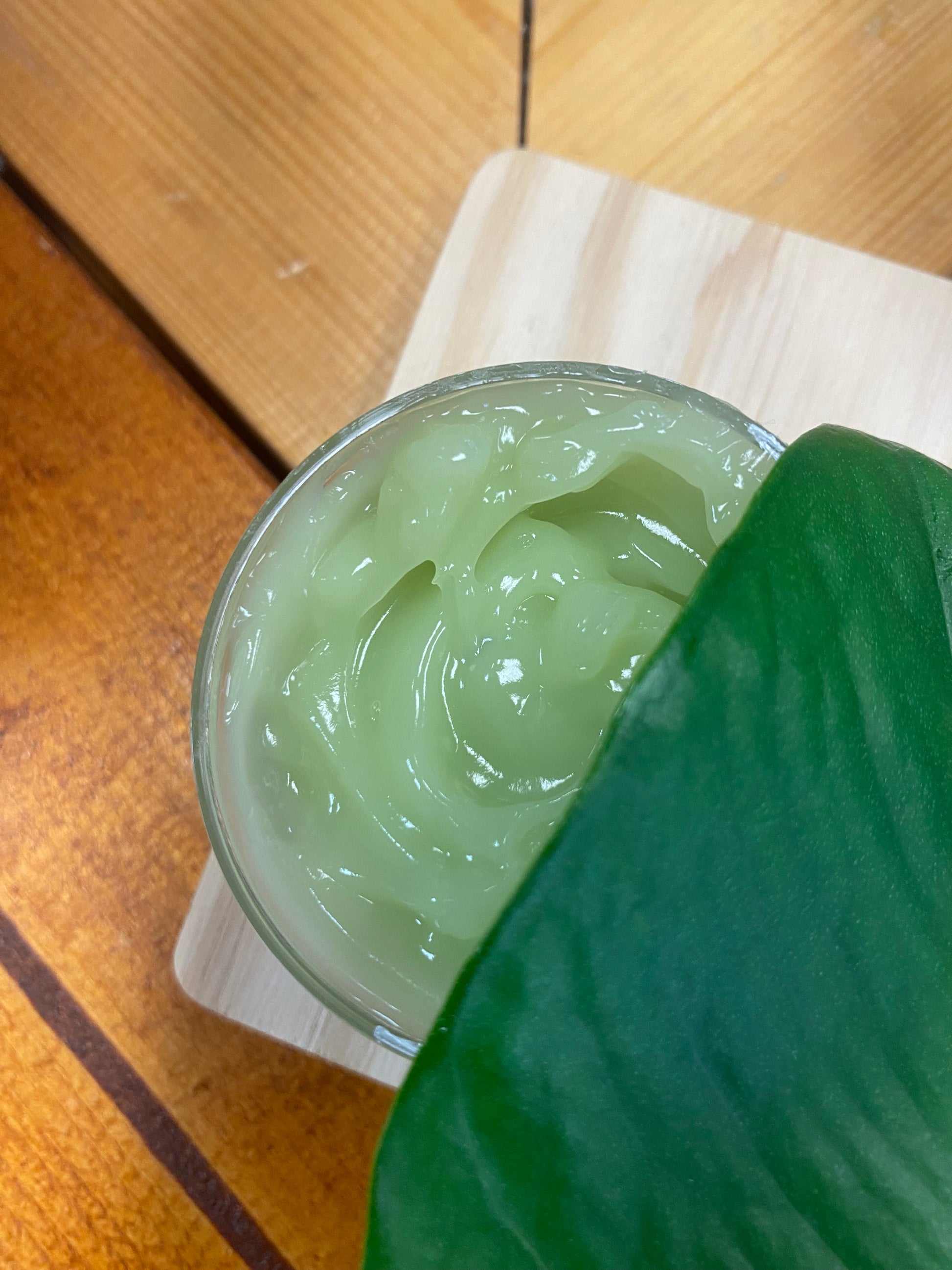Green gel in a jar with a leaf on a wooden surface